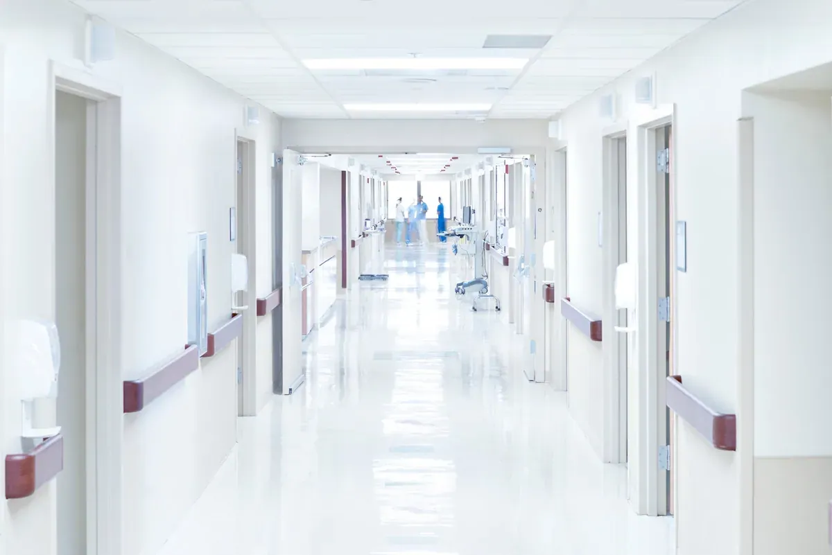Wide hospital corridor kept clear for gurney traffic, a cross-corridor smoke curtain application